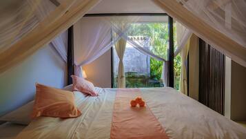 Un dormitorio con cama, almohadas, un objeto decorativo naranja y vistas al exterior.