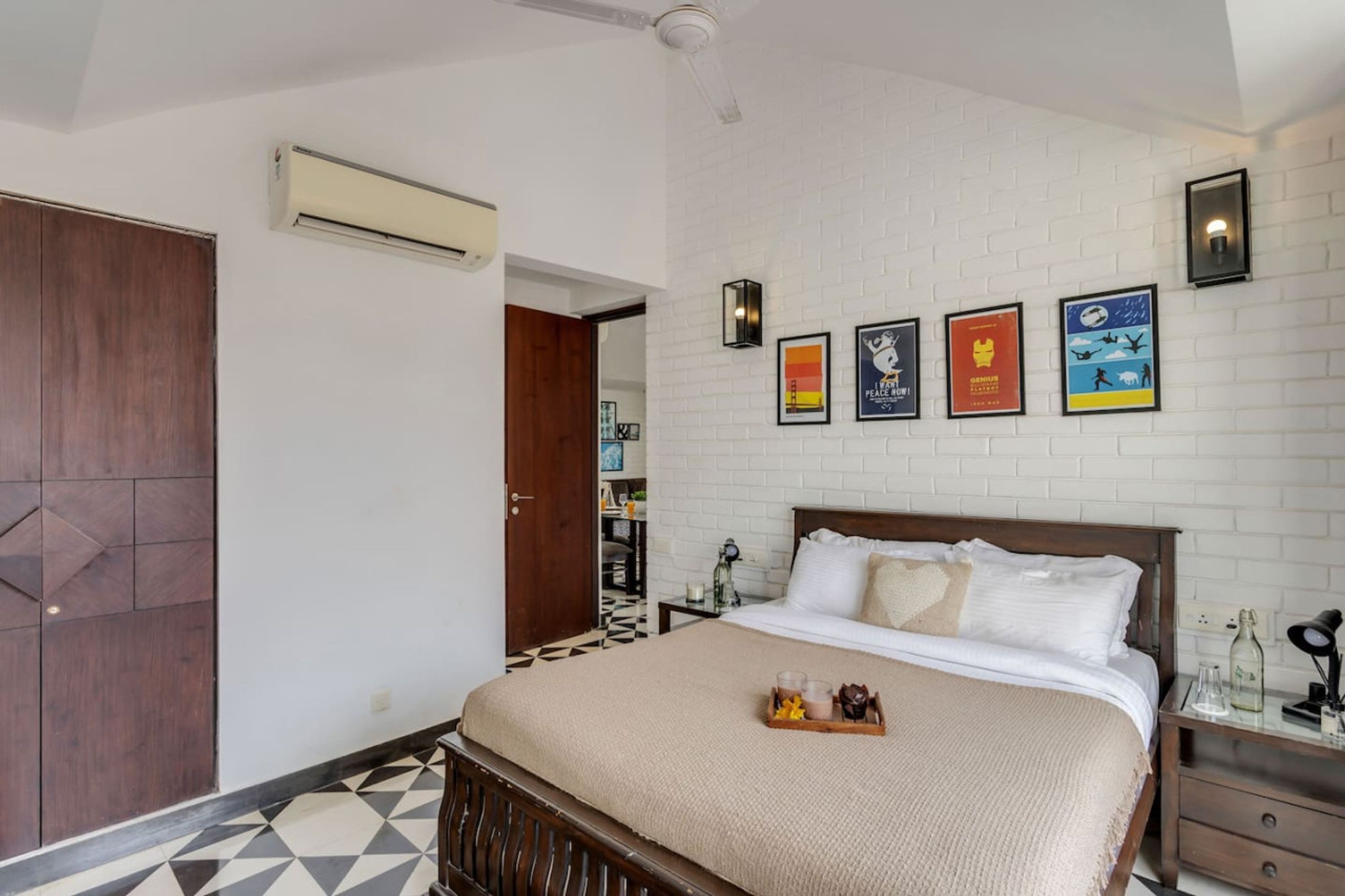 Um quarto com uma cama, um guarda-roupa de madeira, uma parede de tijolos brancos e um ventilador de teto.