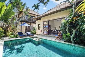 A pool area with lounge chairs, a covered seating area, and tropical plants. - Havara Villa by Kozystay - Private Beach (Ungasan)