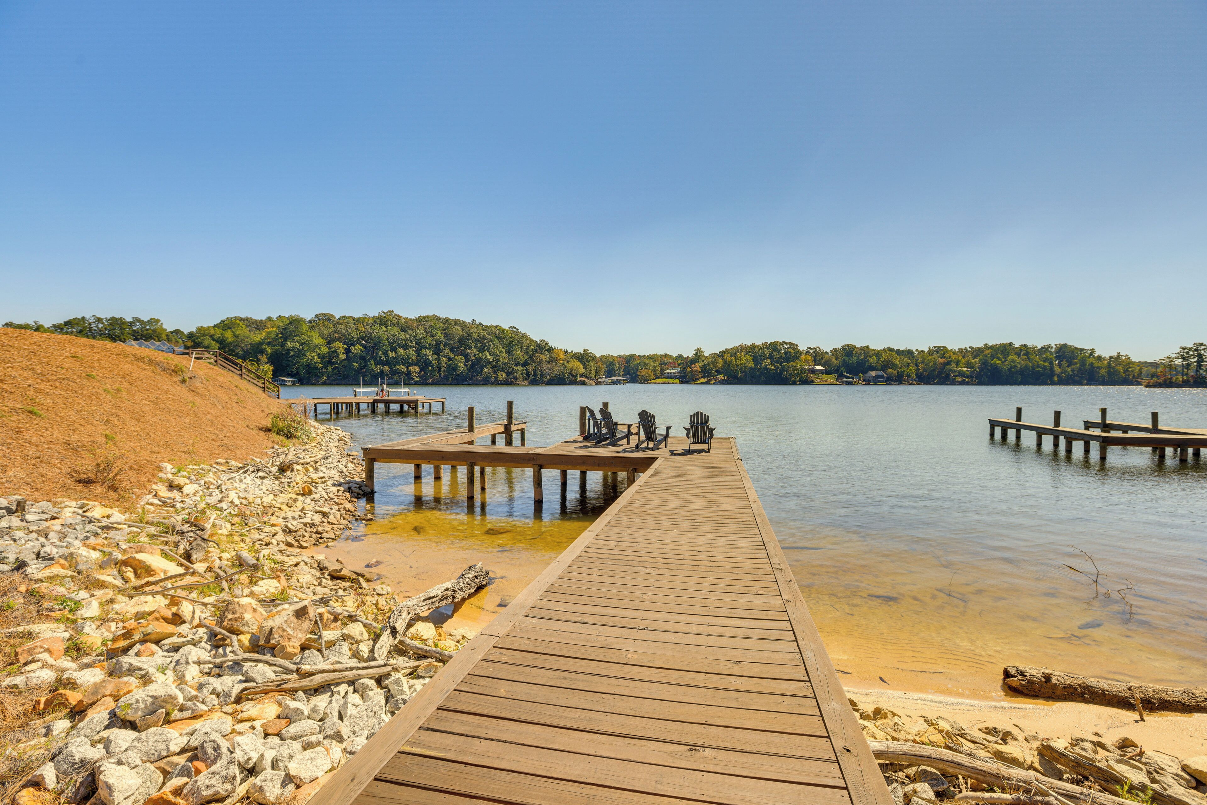 A wooden pier extending into calm water, surrounded by rocky terrain and trees.