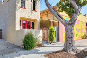 A building with a red door, a tree in front, and a colorful mural on the adjacent wall. - 1 Mi to Ocean! Home w/ Rooftop Deck in Long Beach (Long Beach)