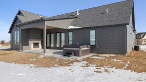 A modern house with a covered patio, a fireplace, and a hot tub. - Beartooth View (Red Lodge)