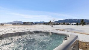 A hot tub in a snowy landscape with houses and mountains in the background. - Beartooth View (Red Lodge)