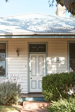 A house with a white door, a small porch, and a sign that reads "Jynygdder".