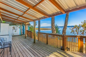 Eine Holzterrasse mit Metallüberdachung, die auf ein Gewässer blickt.