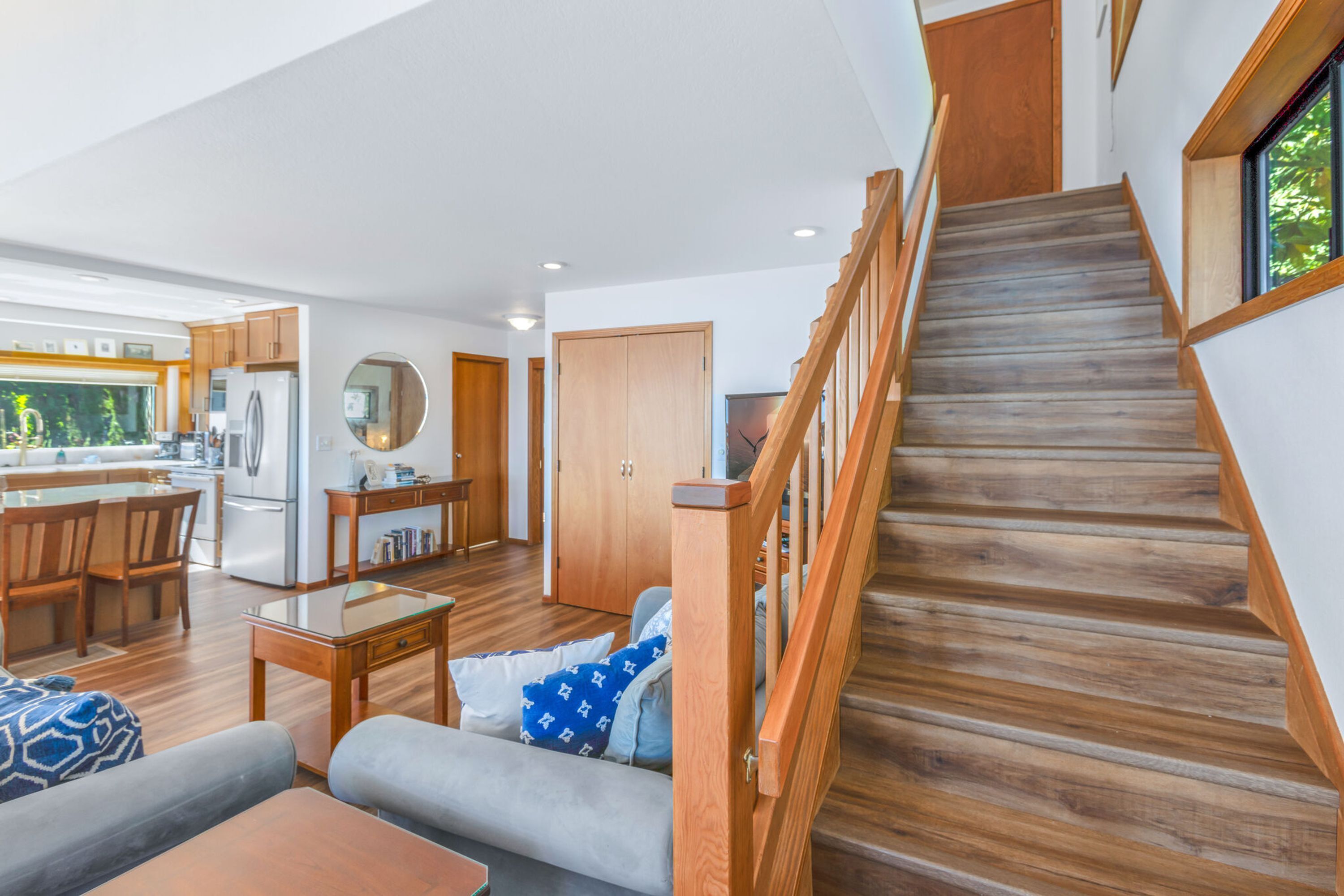 A spacious living area with a wooden staircase, a kitchen, and a dining area.