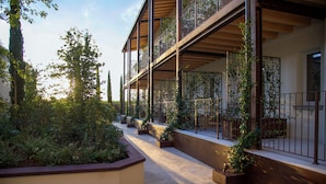 A multi-story building with balconies, outdoor seating areas, and greenery. - Aria Executive Resort  (Travagliato)