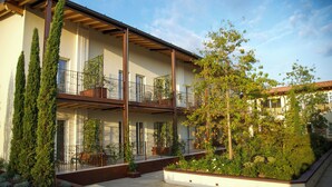 A modern multi-story building with balconies, outdoor seating, and a landscaped garden area. - Aria Executive Resort  (Travagliato)