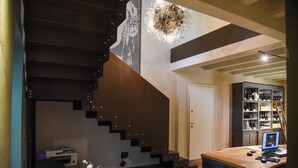 A modern interior with a staircase, a desk with a computer, and a wine rack. - Aria Executive Resort  (Travagliato)