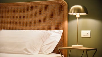A bed with white linens, a wooden headboard, and a bedside table with a lamp.