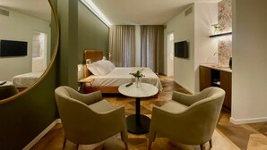 A hotel room with a bed, a round table, two chairs, a large mirror, a TV, and a small desk with a sink. - Aria Executive Resort  (Travagliato)