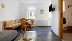 Un salon moderne comprenant un canapé, une table à manger, des chaises, un téléviseur et une cheminée.