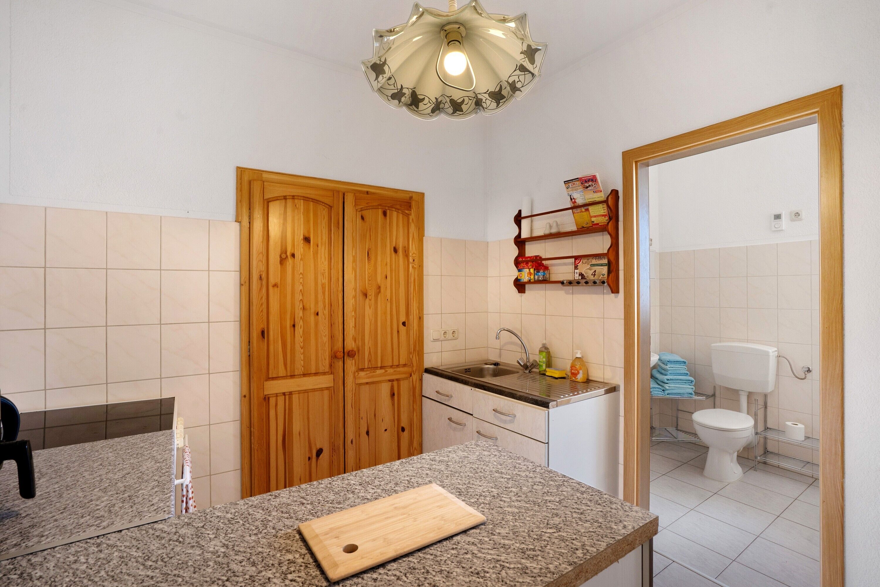 Une cuisine avec des meubles en bois, un plan de travail en granit, un évier et un miroir.