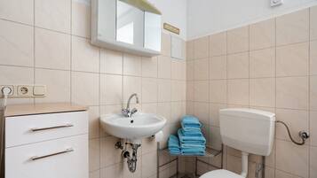 Een badkamer met een wastafel, spiegel, toilet en handdoekhouder.