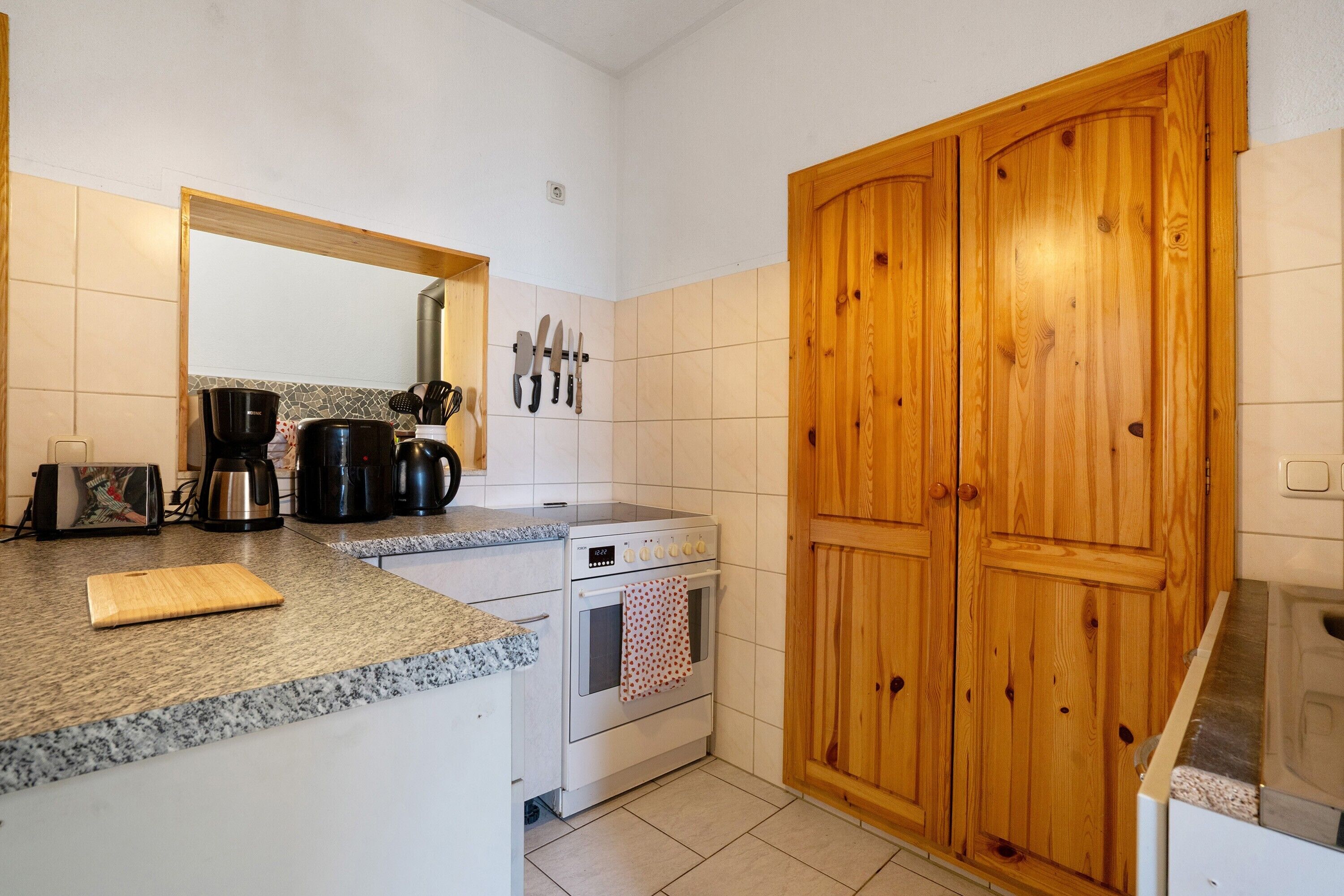 Uma cozinha com bancada de granito, fogão, cafeteira e armários de madeira.