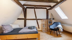 Un dormitorio tipo loft con una cama de madera, una silla, una estantería y un tragaluz.