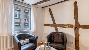 Una habitación con vigas de madera a la vista, un radiador, dos sillones de cuero y una pequeña mesa con cristalería decorativa.