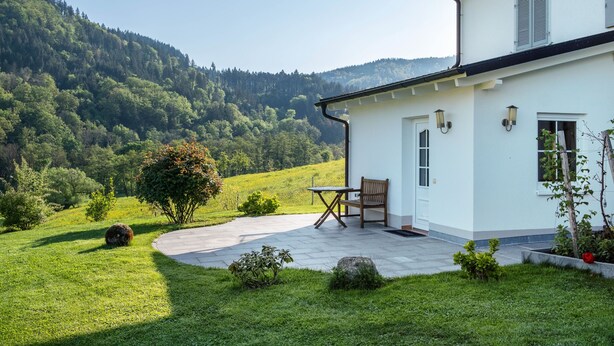 Een huis met een terras, een tafel en een stoel.