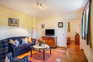 Un salon avec un canapé, un téléviseur, un meuble en bois et un tableau accroché au mur.
