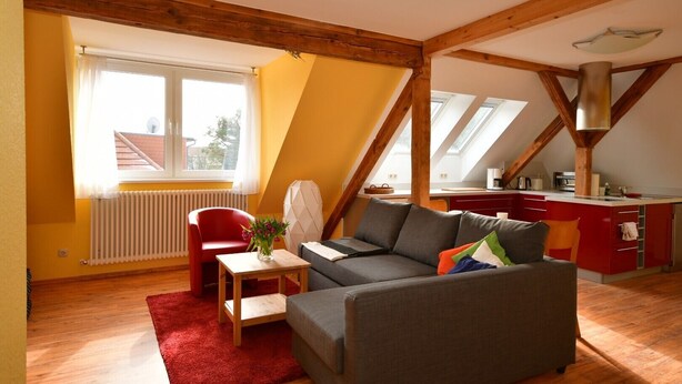 Un appartement-loft confortable avec un coin repas, une cuisine et un fauteuil rouge.