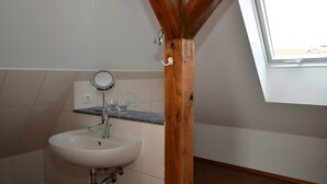 Une salle de bain avec un lavabo blanc, un miroir et une fenêtre.