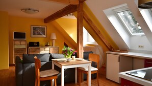 Une pièce chaleureuse avec un plafond en bois, une table à manger, un canapé et une petite kitchenette.