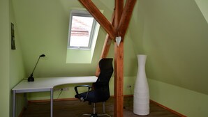 Une pièce comprenant un bureau, une chaise, une fenêtre et un vase blanc.