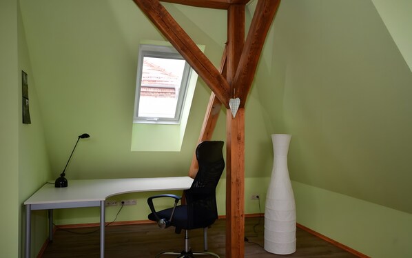 Une pièce comprenant un bureau, une chaise, une fenêtre et un vase blanc.
