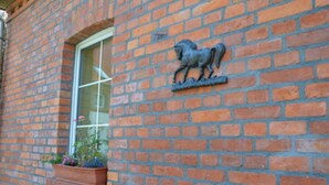 Un edificio de ladrillo con una ventana y una escultura de un caballo de metal.
