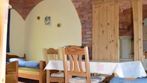 Una habitación con techo de ladrillo, una mesa de madera con sillas, una cama y un sofá azul.