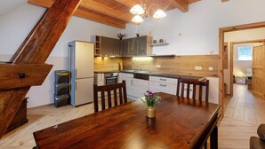 A kitchen with wooden cabinets, a dining table with chairs, and a hanging light fixture.