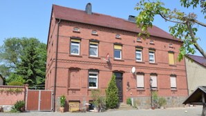 A red brick building with a symmetrical facade, multiple windows, and a central entrance.