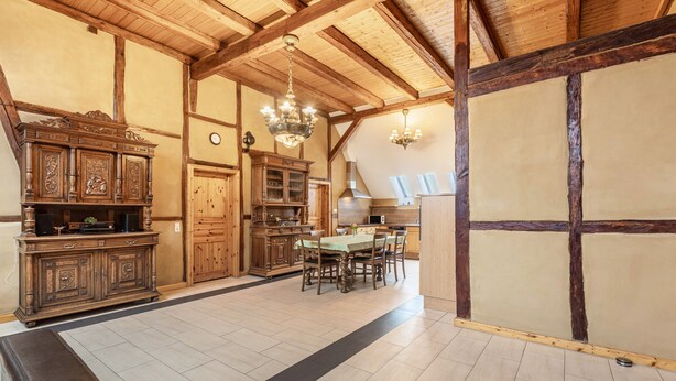 Ein traditionelles Gasthaus mit freiliegenden Holzbalken, einem Essbereich mit Tisch und Stühlen sowie einem großen Holzkasten.