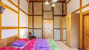 Ein Zimmer mit einem Bett, einem Stuhl, Holzwänden und einer Tür.