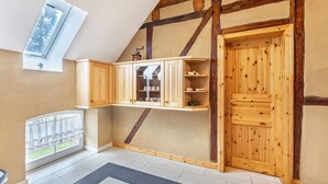 Ein Zimmer mit geneigter Decke, Holzschränken, einem Heizkörper und einer Tür.