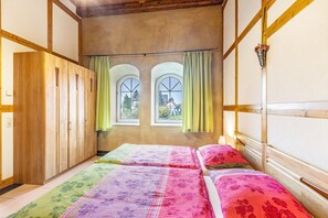 A room with a bed, a wardrobe, and two windows with curtains.