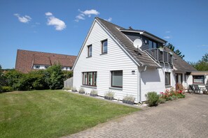 A two-story house with a sloped roof, a satellite dish, and a paved driveway.
