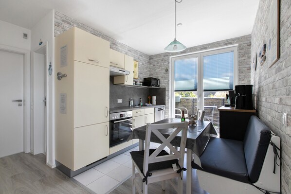 A compact kitchen with a dining area, a built-in oven, and a seating bench.