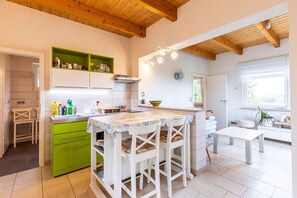 Een keuken met een groen eiland, witte kastjes en een houten plafond.