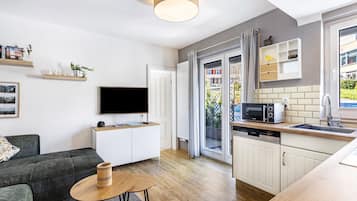 Un appartement moderne comprenant un salon, une cuisine et une porte-fenêtre coulissante donnant sur l’extérieur.