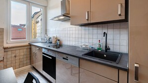Eine moderne Küche mit Geschirrspüler, Spüle und Fenster mit Blick auf eine Stadtlandschaft.