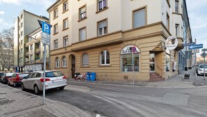 Ein mehrgeschossiges Gebäude mit einem Laden im Erdgeschoss, einem Parkschild und einer Straßenszene.