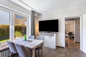 Una habitación moderna con una mesa de comedor, sillas, un televisor de pantalla plana y una zona de cocina.