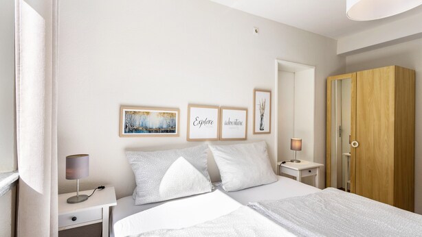 A bedroom with a bed, bedside tables, a wardrobe, and wall art. - Holiday Apartments Löwenstein FeWo 1 with Private Terrace & Garden and Wi-Fi (Willingen (Upland))