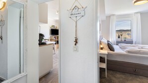 A bedroom with a bed, a window with a view, a bedside table, and a wall-mounted welcome sign. - Holiday Apartments Löwenstein FeWo 3 with Private Terrace, Shared Garden and Wi-Fi (Willingen (Upland))