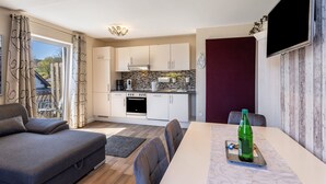 A modern kitchen with white cabinets, a built-in oven, and a stone backsplash.