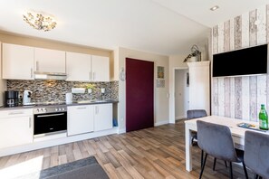 Eine moderne Küche mit weißen Schränken, einer Steinrückwand und einem eingebauten Backofen.