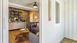 A modern kitchen with a black backsplash, a dining area with a round table, and a living room with a sofa and a lamp.