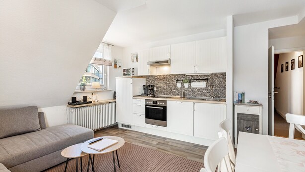 A modern kitchen with white cabinets, a brick backsplash, and a built-in oven.