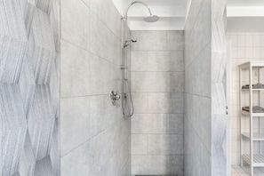 A shower with a handheld showerhead, a wall-mounted faucet, and a control knob.